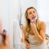 Frau trägt den INUANA Gesichtsöl Stick im Bad vor dem Spiegel auf ihre Lippen auf.