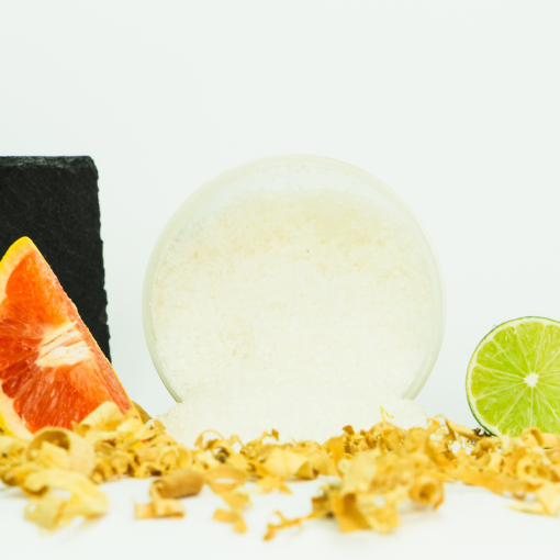 Duft-Badesalz Signature als pflegender Badezusatz von INUANA umgeben von Limette, Grapefruit und Holzspänen