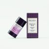 Der INUANA Haarwax Stick Nectarine und Musk steht neben seiner violetten Verpackung vor hellem Hintergrund.