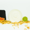 Geöffneter Tiegel Zuckerpeeling von INUANA umgeben von Limette, Grapefruit und dekorativen Holzspänen für natürliche Körperpflege