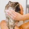 Eine Person schäumt das feste Shampoo von INUANA für eine reinigende Haarpflege sanft im nassen Haar auf.