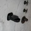 Schwarzer Wand-Seifenspender von INUANA an hellem Marmor in der Dusche für sanfte Duschpflege.