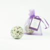 INUANA Badekugel Velvet Sandalwood Lavender vor verpacktem Produkt im lila Beutel als natürlicher Badezusatz