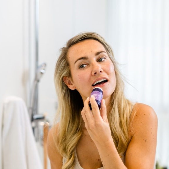 Person trägt den INUANA Face Zinc Balm Stick für eine beruhigende Gesichtspflege im Badezimmer auf.