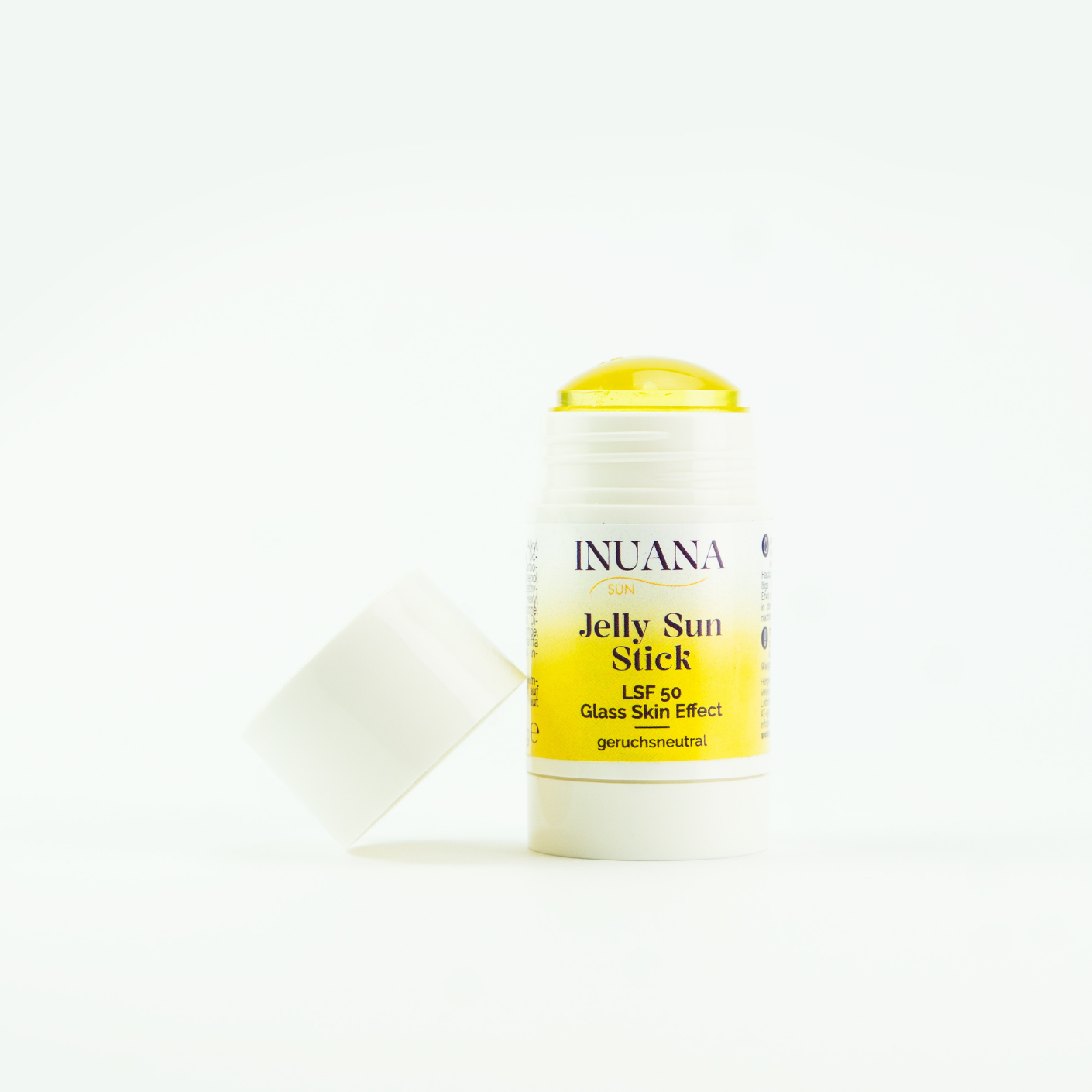 Geöffneter INUANA Jelly Sun Stick LSF 50 mit gelb-transparenter Textur neben der weißen Verschlusskappe.