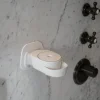 Weißer Wand-Seifenspender von INUANA an einer hellem Marmorwand in der Dusche für sanfte Duschpflege.